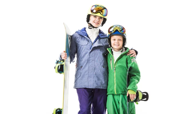 Sorrindo mãe e filho pré-adolescente em trajes de esqui com snowboards abraçando e olhando para a câmera isolada no branco — Fotografia de Stock