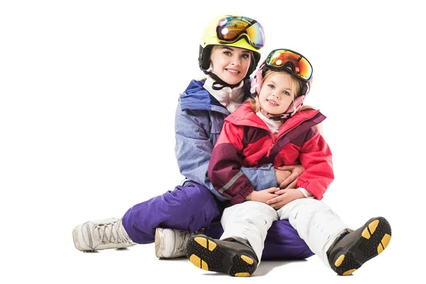 Pretty woman embracing preschooler daughter in ski suit and looking at camera isolated on white — Stock Photo