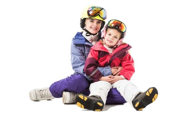 Hübsche Frau umarmt Vorschultochter im Skianzug und blickt vereinzelt in die Kamera — Stockfoto