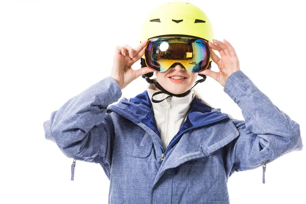 Junge Frau in blauer Skijacke, Schutzbrille und Helm lächelt vereinzelt auf weißem Grund — Stockfoto