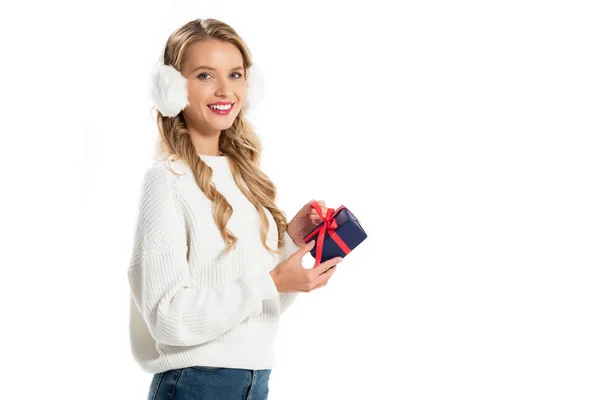 Attractive young woman in winter earmuffs holding little gift isolated on white — Stock Photo