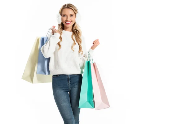 Mujer alegre en traje de invierno sosteniendo bolsas de compras aisladas en blanco - foto de stock