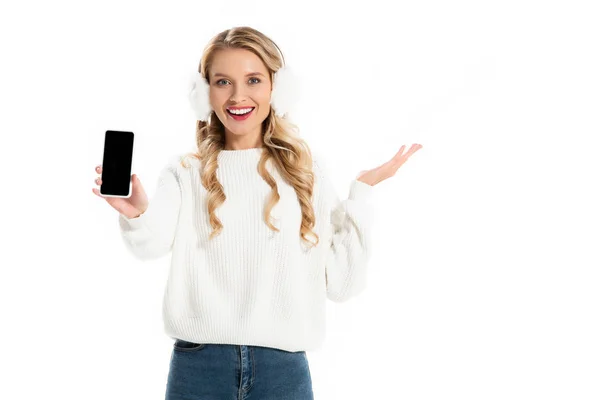 Chica excitada en orejeras mostrando teléfono inteligente con pantalla en blanco aislado en blanco - foto de stock