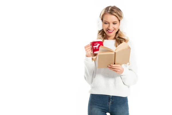 Bela menina sorridente segurando xícara de café e leitura livro isolado no branco — Fotografia de Stock