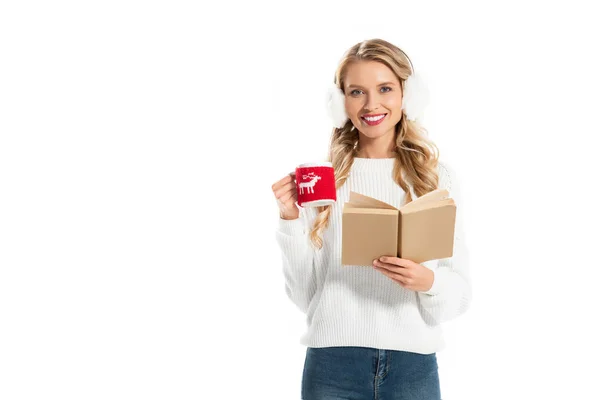 Hermosa chica en traje de invierno sosteniendo libro y taza de café aislado en blanco - foto de stock