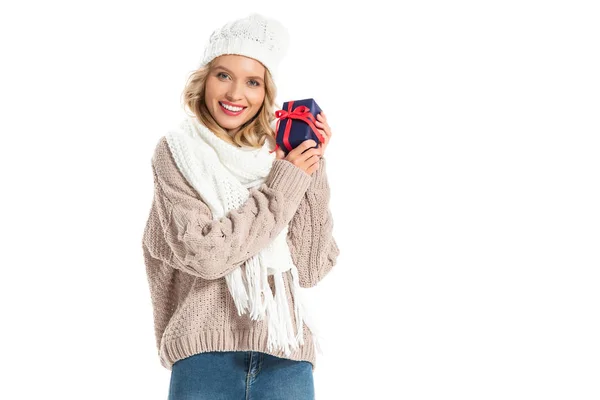 Hermosa mujer joven sonriente en traje de invierno sosteniendo poco regalo aislado en blanco - foto de stock