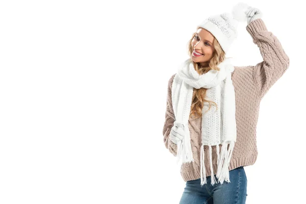 Веселая молодая женщина в бежевом вязаном свитере, белой шляпе, варежках и шарфе улыбается изолированно на белом — стоковое фото
