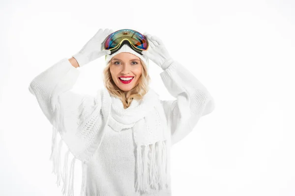 Attractive young adult woman in warm clothes with ski goggles on head smiling and looking at camera isolated on white — Stock Photo