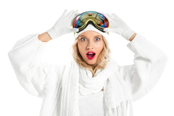 Surprise jeune femme tenant des lunettes de ski sur la tête et regardant la caméra isolée sur blanc — Photo de stock