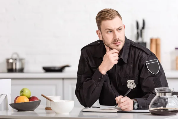 Thoughtful policeman sitting at kitchen table — Stock Photo