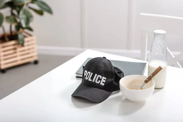 Taccuino, cuffia della polizia e ciotola con colazione sul tavolo bianco — Foto stock