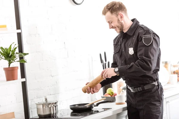 Police officer peppering breakfast at stove in morning — Stock Photo