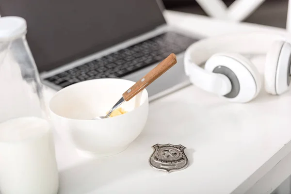 Laptop, headphones, police badge and bowl with breakfast on white table — Stock Photo