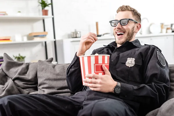 Glücklicher Polizist in 3D-Brille sitzt auf Couch, isst Popcorn und guckt Film — Stockfoto