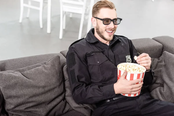 Policeman in 3d glasses sitting on couch, eating popcorn and watching movie — Stock Photo