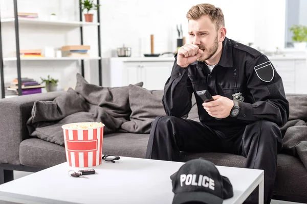 Policeman with scared face expression sitting on couch and watching movie — Stock Photo