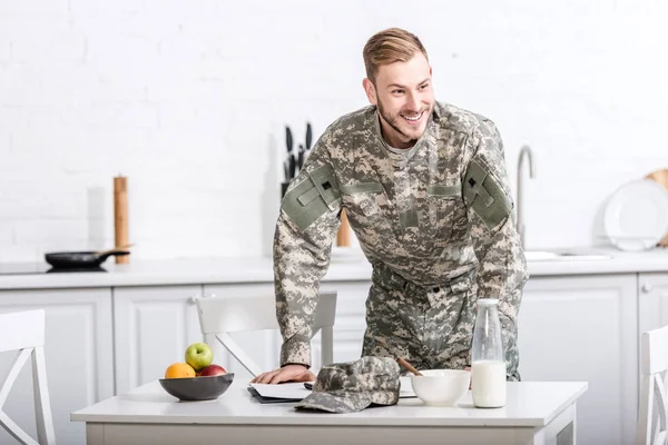 Soldado del ejército en la mesa de la cocina desayunando - foto de stock