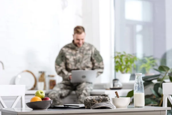 Selective focus of army soldier working on laptop in kitchen — Stock Photo