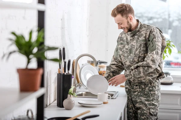 Army soldier cleaning dishes in kitchen — Stock Photo