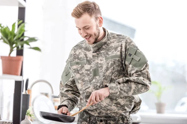 Smiling army soldier cooking on pan in kitchen — Stock Photo