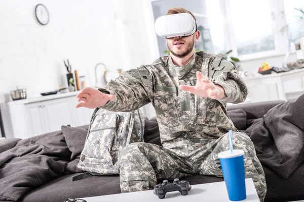 Army soldier touching air during vr experience on couch — стоковое фото