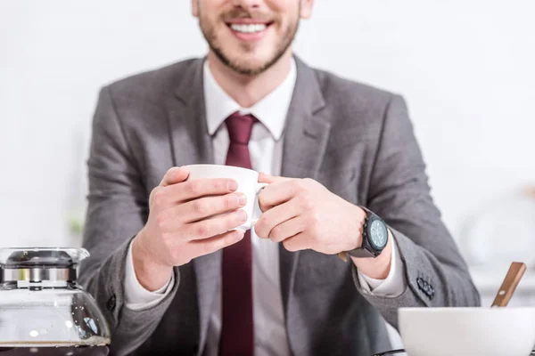 Recortado vista de sonriente hombre de negocios beber café en la cocina - foto de stock