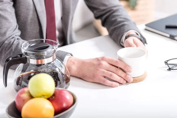 Vista recortada de hombre de negocios beber café en la cocina - foto de stock