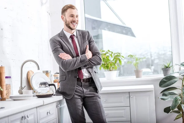 Uomo d'affari sorridente con braccia incrociate in cucina — Foto stock