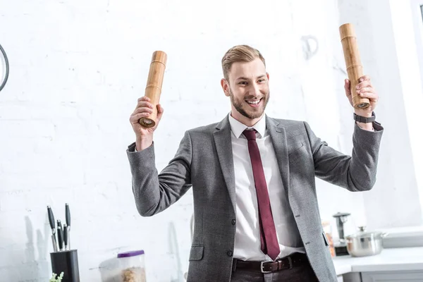 Excited businessman holding pepper pots and getting ready to cook in kitchen — Stock Photo