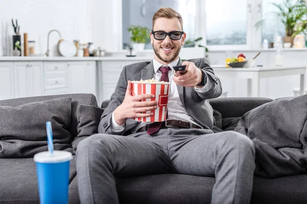 Schöner Geschäftsmann auf der Couch in 3D-Brille mit Fernbedienung beim Filmgucken und Popcorn essen — Stockfoto