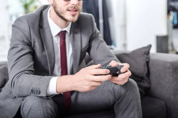 Cropped view of businessman holding console and playing video game at home — Stock Photo