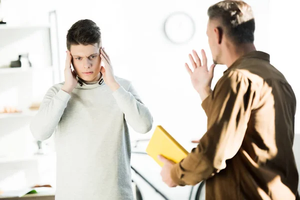 Irritated father gesturing and yelling at teen son at home — Stock Photo