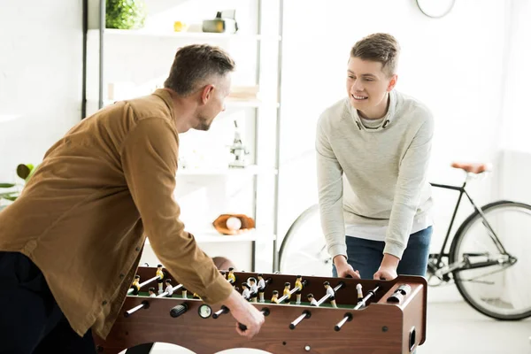 Father and teen son playing table football together at home — Stock Photo