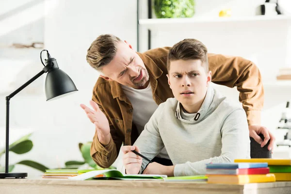 Colère père geste et crier à adolescent fils, garçon couvrant oreilles — Photo de stock