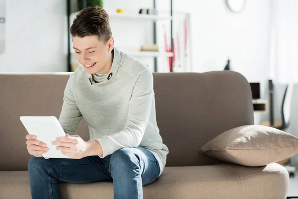 Adolescente sorrindo usando tablet no sofá em casa — Fotografia de Stock