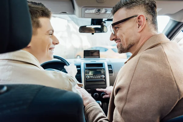 Side view of happy handsome father and teen son looking at each other in car — Stock Photo