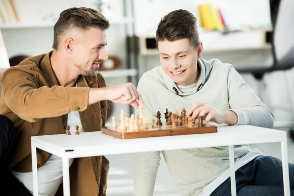 Felice padre e figlio adolescente giocare a scacchi insieme a casa — Foto stock