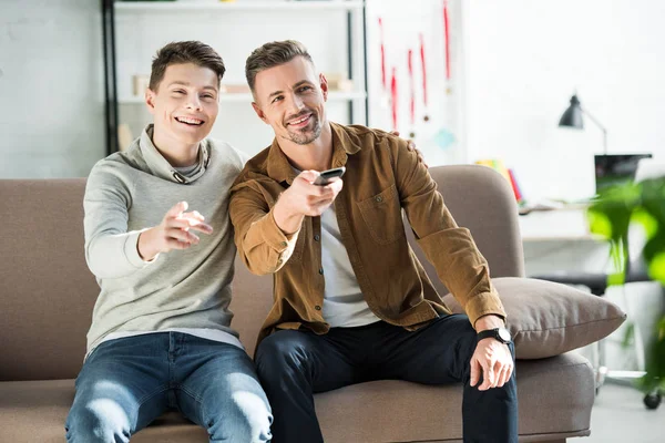 Sonriente padre y adolescente hijo viendo tv juntos en casa - foto de stock