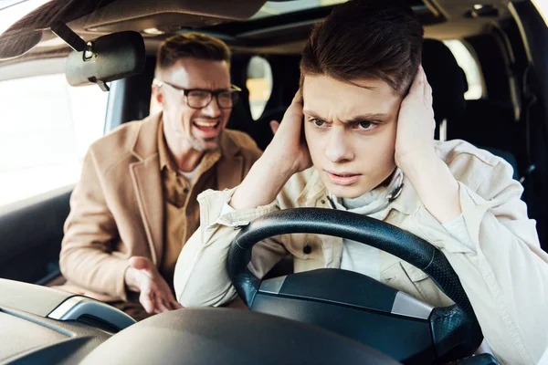 Раздраженный отец кричит на сына-подростка в машине — стоковое фото
