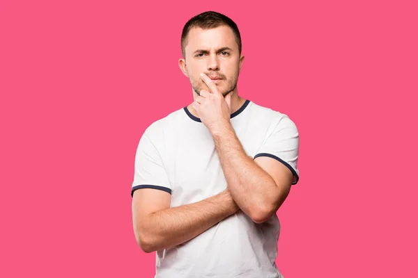 Nachdenklicher junger Mann mit Finger am Kinn isoliert auf rosa — Stockfoto