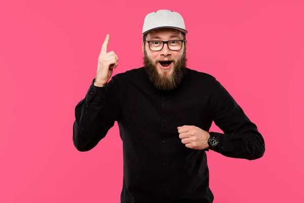 Aufgeregter bärtiger Mann mit Brille und Mütze macht Ideengeste isoliert auf rosa — Stockfoto