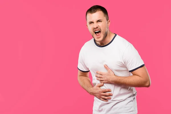 Сердитий чоловік кричить і болить шлунок ізольовано на рожевому — стокове фото
