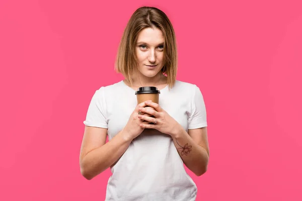 Schöne junge Frau mit Einwegbecher Kaffee isoliert auf rosa — Stockfoto