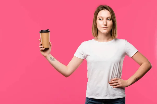Muito tatuado menina mostrando descartável xícara de café isolado no rosa — Fotografia de Stock