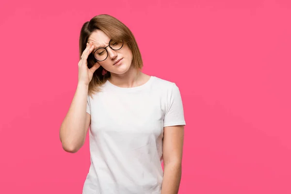 Mujer joven enojada en gafas con dolor de cabeza aislado en rosa - foto de stock
