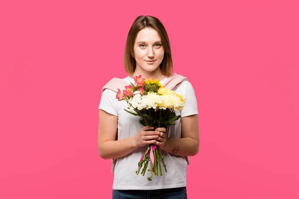 Smiling young woman holding colorful bouquet from various flowers isolated on pink — Stock Photo