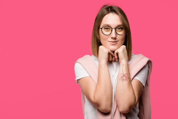 Fröhliche junge Frau mit Brille blickt vereinzelt in die Kamera auf rosa — Stockfoto