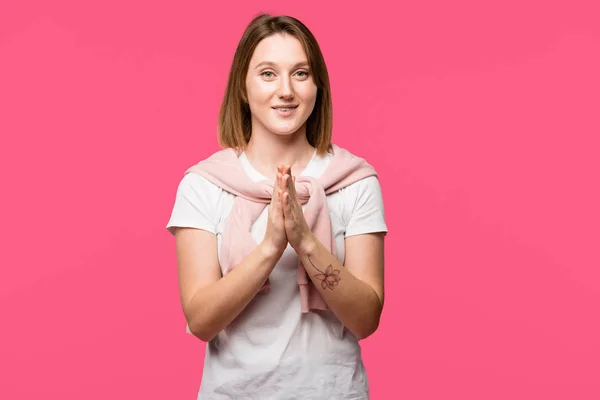 Joyful young woman looking at camera with hand palms together isolated on pink — Stock Photo