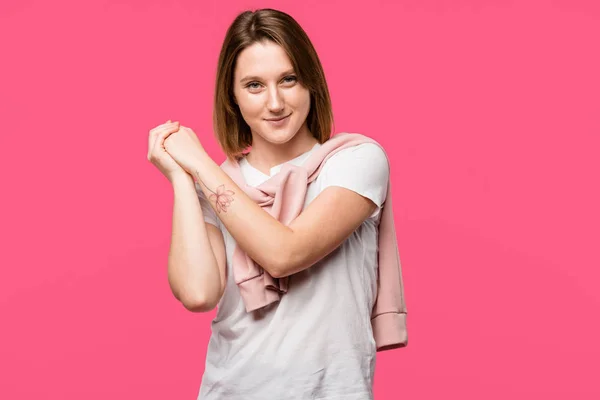 Felice giovane donna con i palmi della mano incrociati guardando la fotocamera isolata su rosa — Foto stock