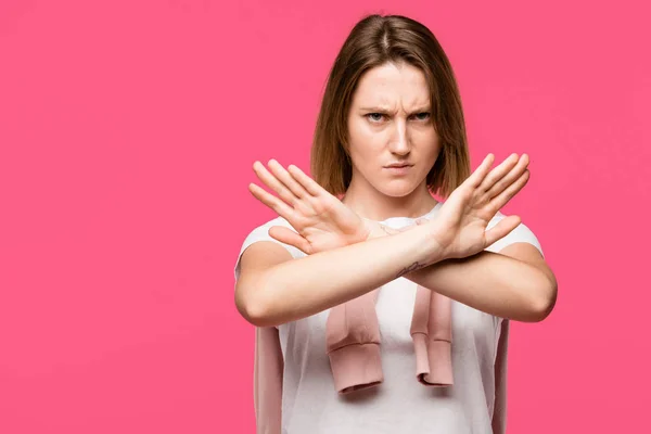 Angry young woman showing stop gesture with crossed arms isolated on pink — Stock Photo